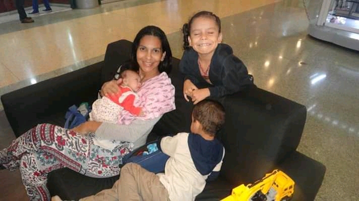 isabella bebé con síndrome de down en brazos de su mamá y a lado su hermana y hermano